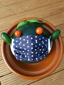 Melone mit einer Stoffmaske als Gesicht