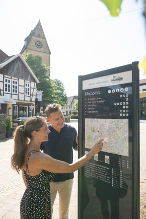 Mann und Frau vor einer Informationstafel im Stadtkern von Steinhagen